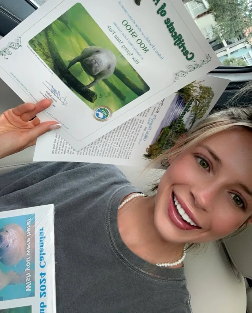 Bexx smiling and holding Moo Shoo's adoption certificate from Save the Manatee Club