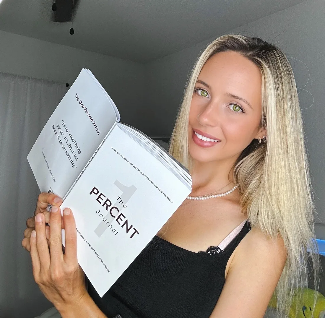 Bexx, CEO and founder of Savvy Squirrel Social, holding The One Percent Journal