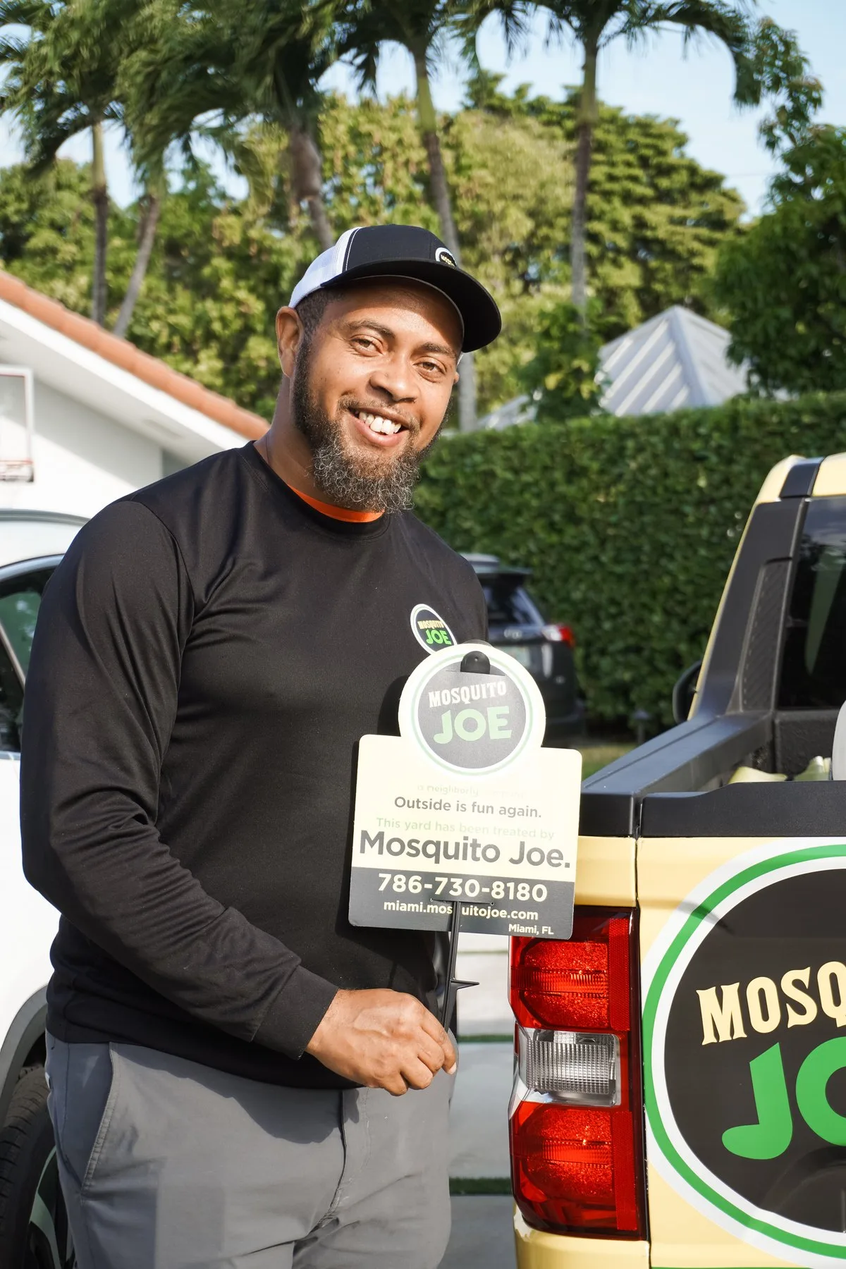 A Mosquito Joe technician with a treated-yard sign